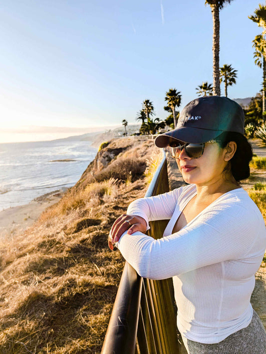 Woman in hiking streetwear enjoying a scenic ocean view, showcasing stylish and functional outdoor fashion.